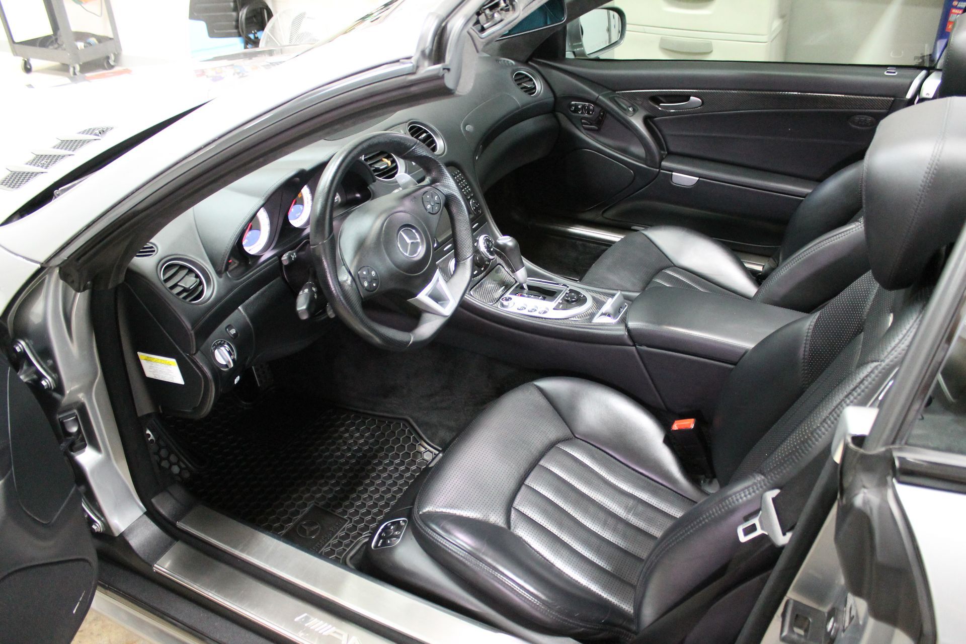 Interior view of a black leather car, possibly a convertible. The steering wheel and seats are visible.