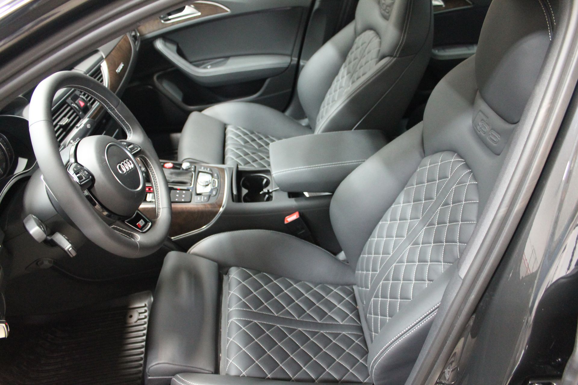 Black leather car interior with diamond-stitched seats, steering wheel, and console.