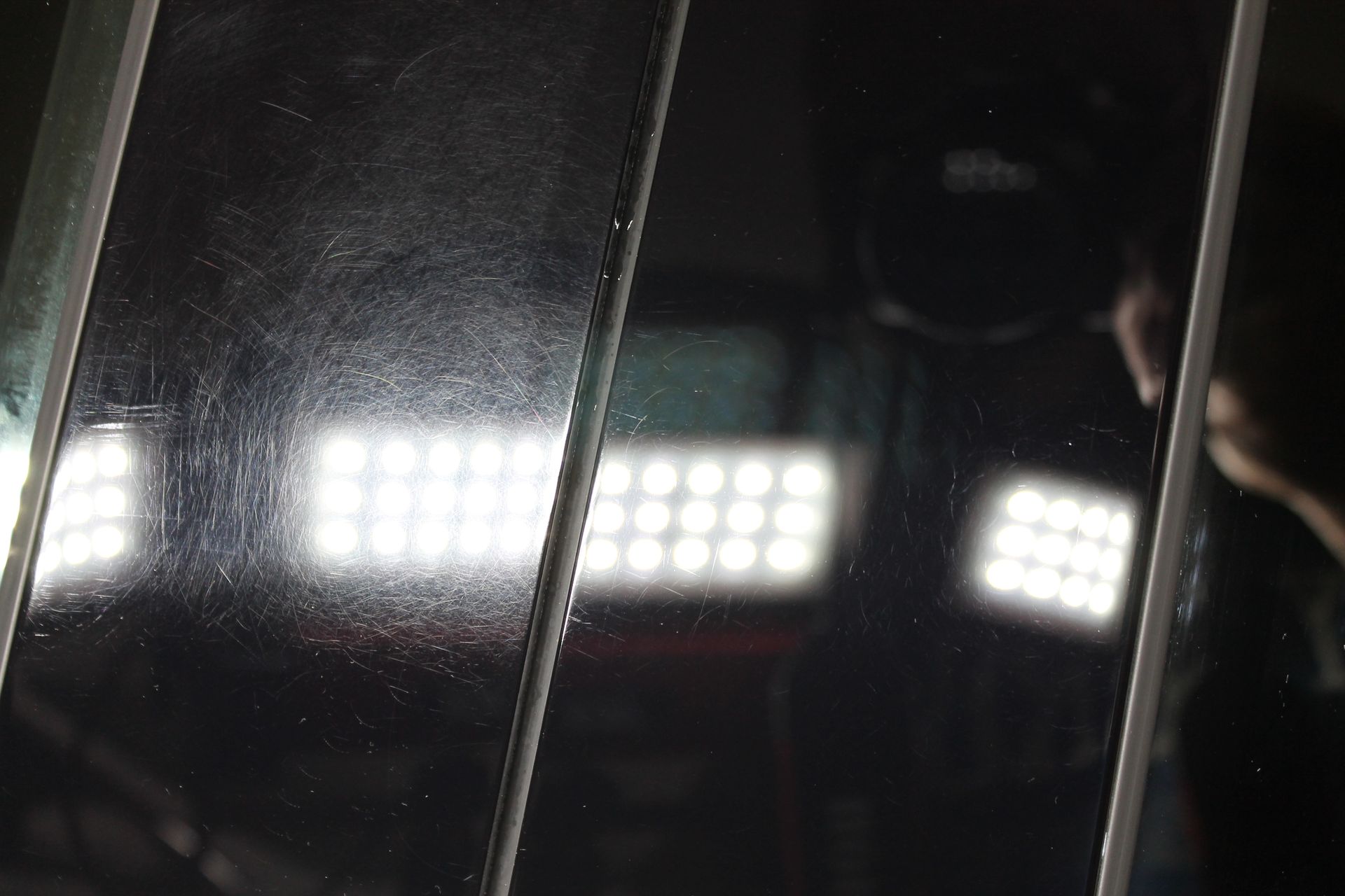 Comparison of two black surfaces: one scratched, one polished. Bright lights reflect.