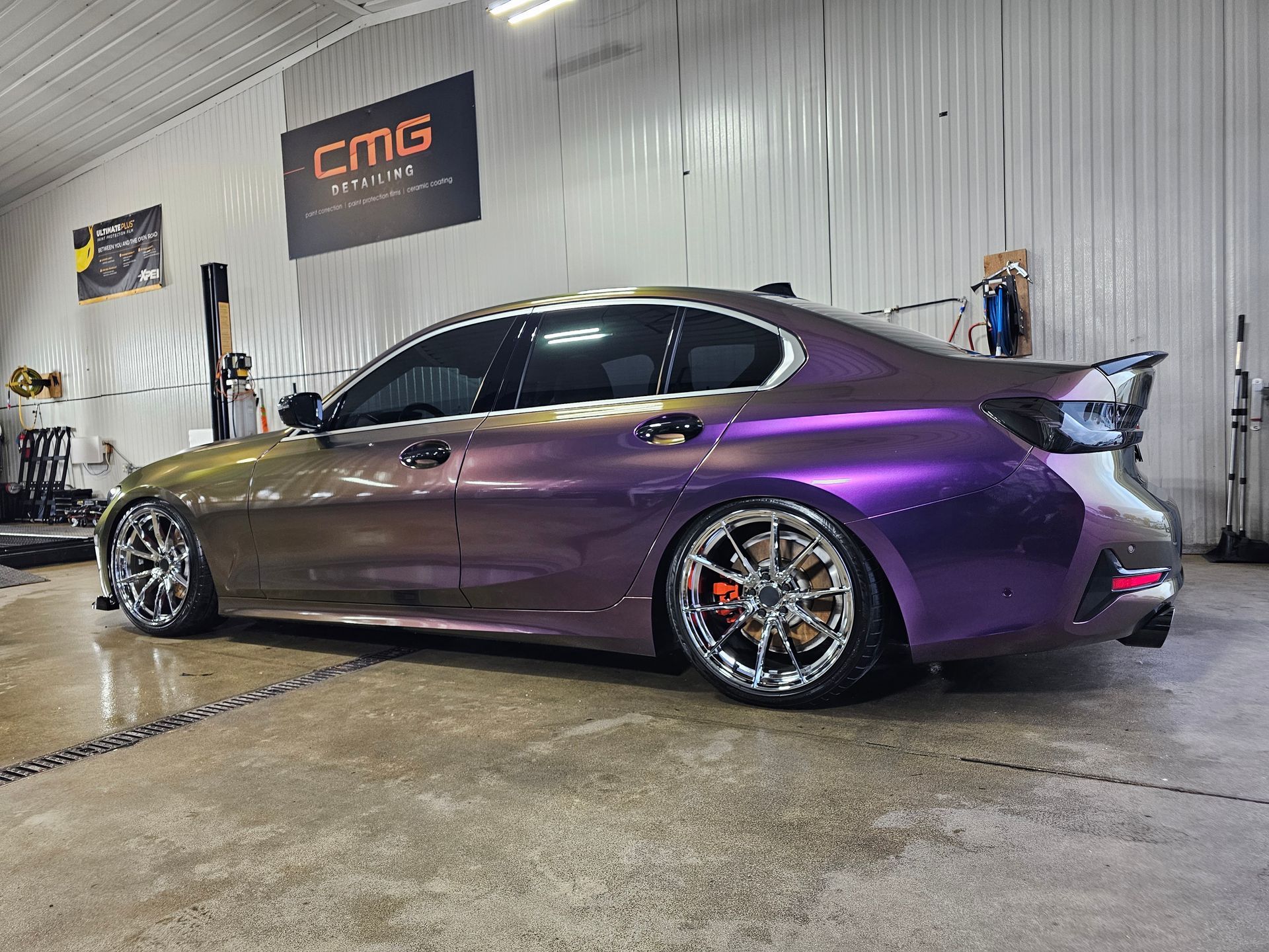 Customized car in a garage with a purple and gold color shift wrap.