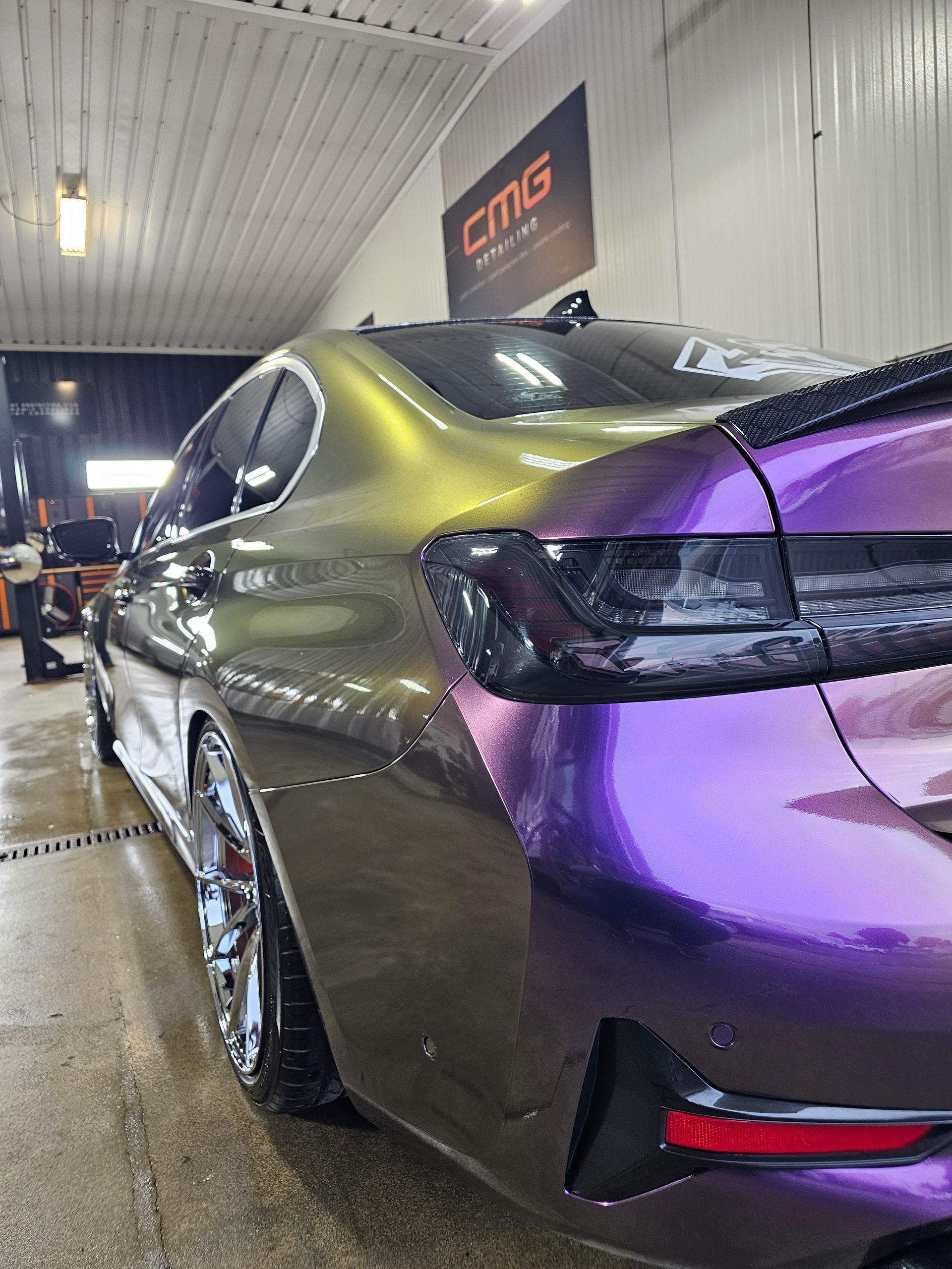 A two-tone, color-shifting BMW sedan in a car wash, with purple and gold hues.
