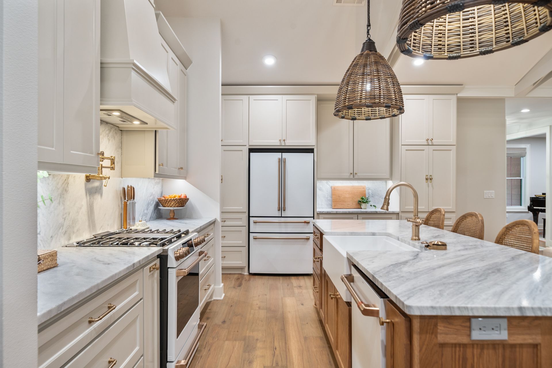 Modern kitchen featuring light cabinetry, marble countertops, a wooden island, and woven pendant lights.
