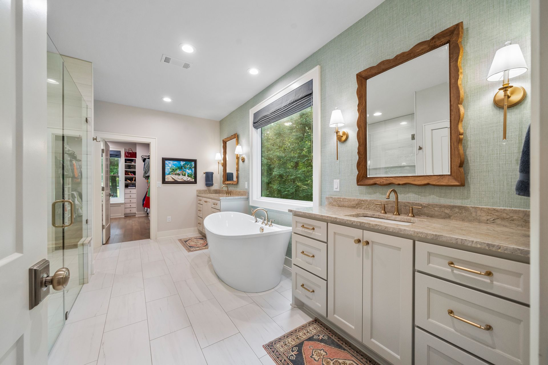 A bright, elegant bathroom featuring a freestanding white tub, a double vanity with a mirror, and a glass-enclosed shower.