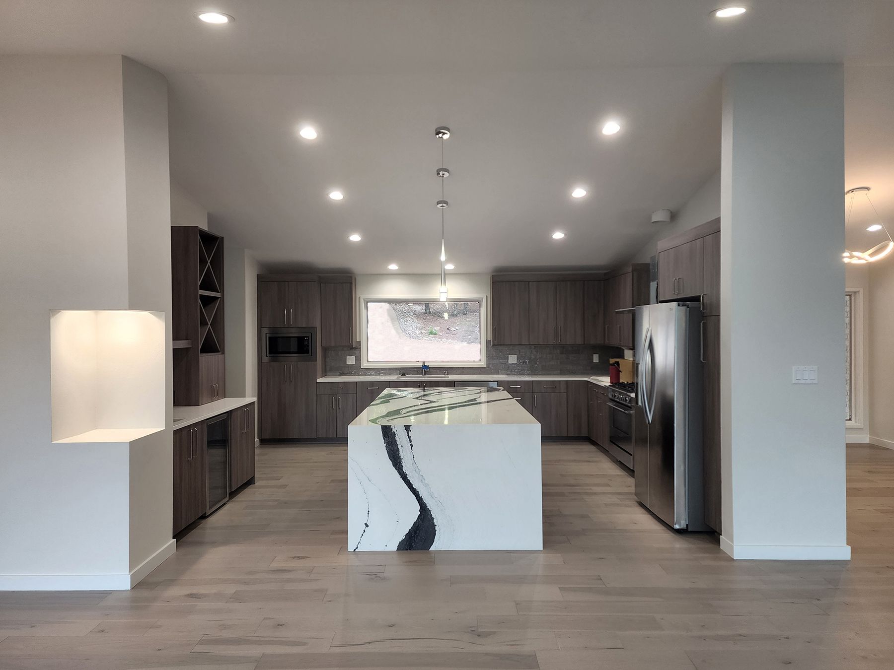 A living area featuring a brown leather sofa, dining table, and a small kitchenette with white cabinets on hardwood floors.
