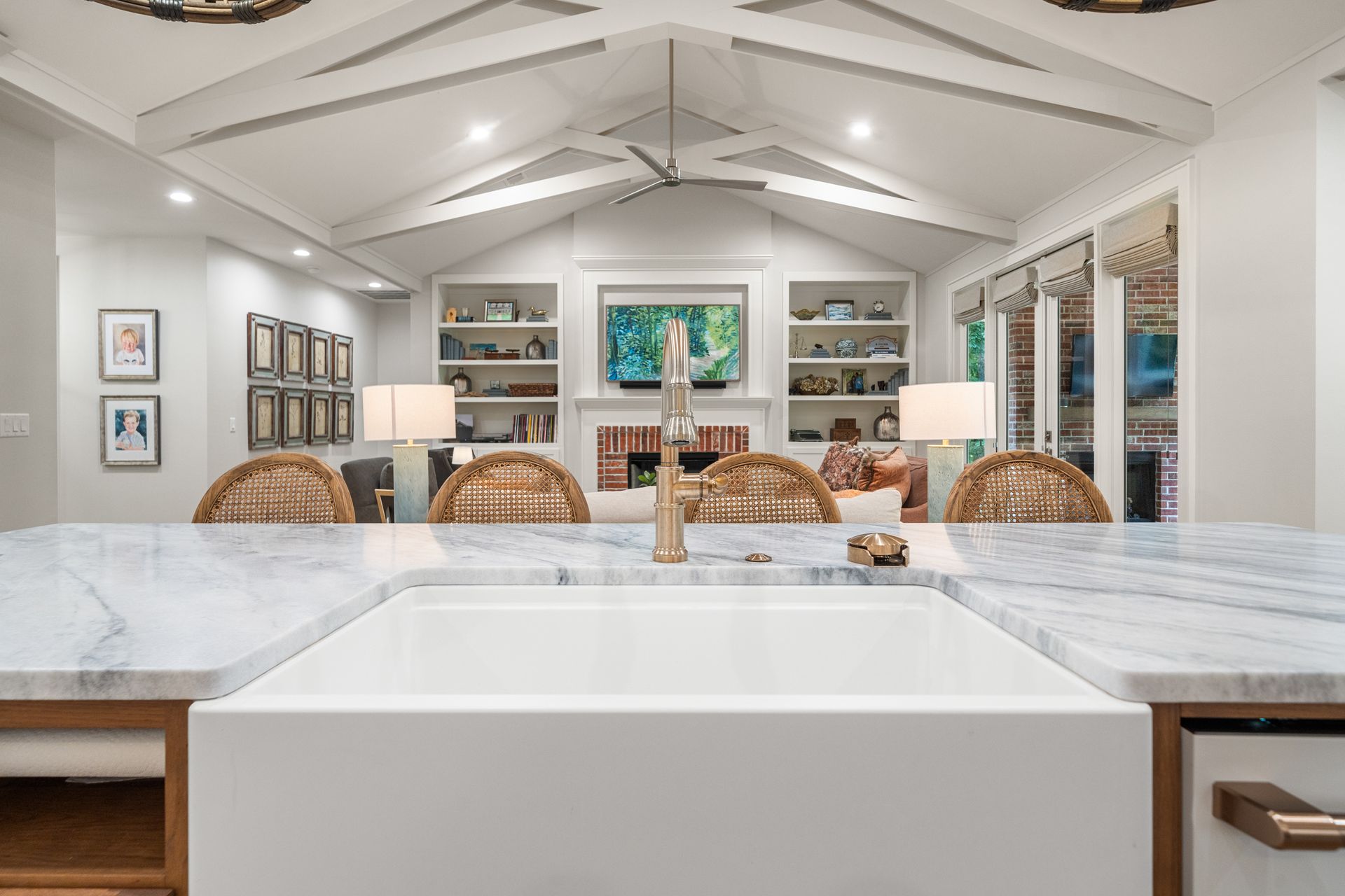 An open sunroom with a wood-slatted ceiling, dining table, and seating area featuring a fireplace and large windows.