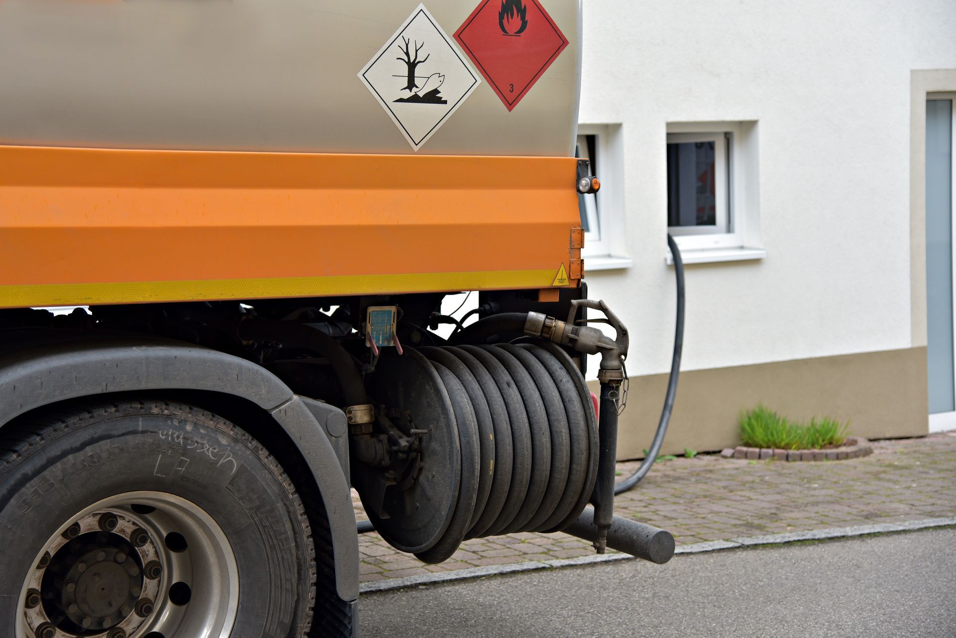 Oil truck parked near home delivering hesidential home heating oil with hose connection.