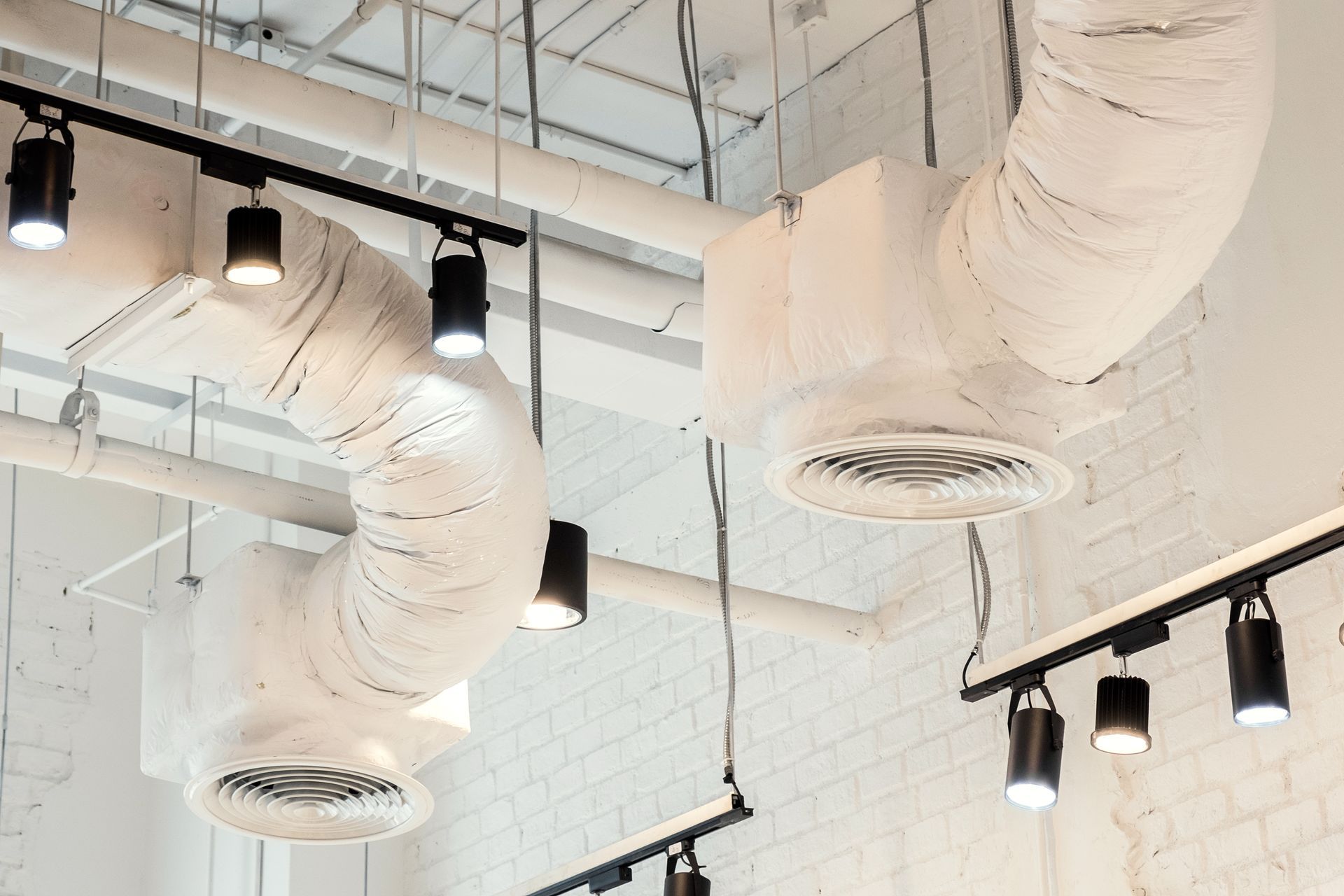 White ceiling with exposed ventilation ducts and track lighting.