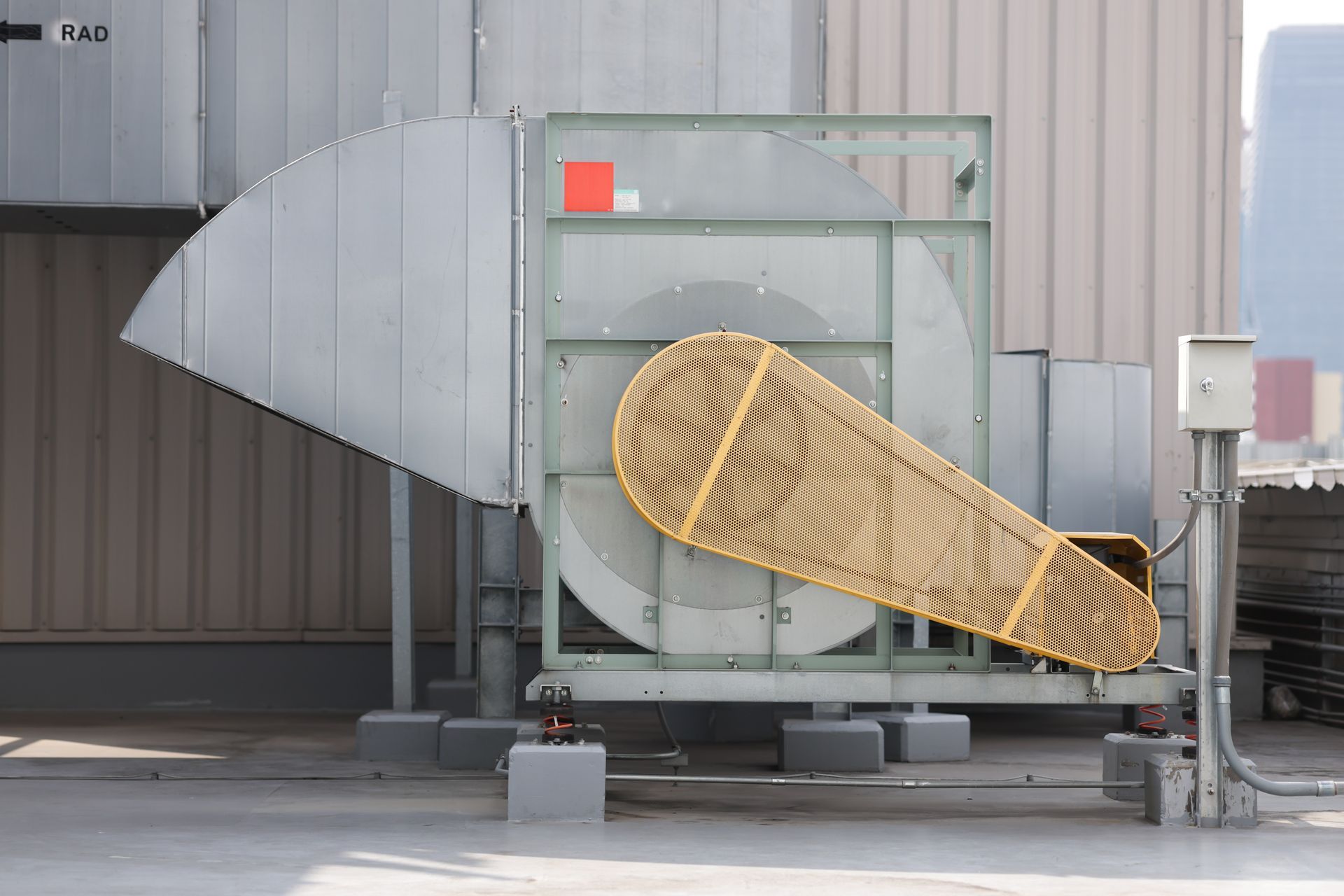 Large industrial blower with protective guard on a rooftop.