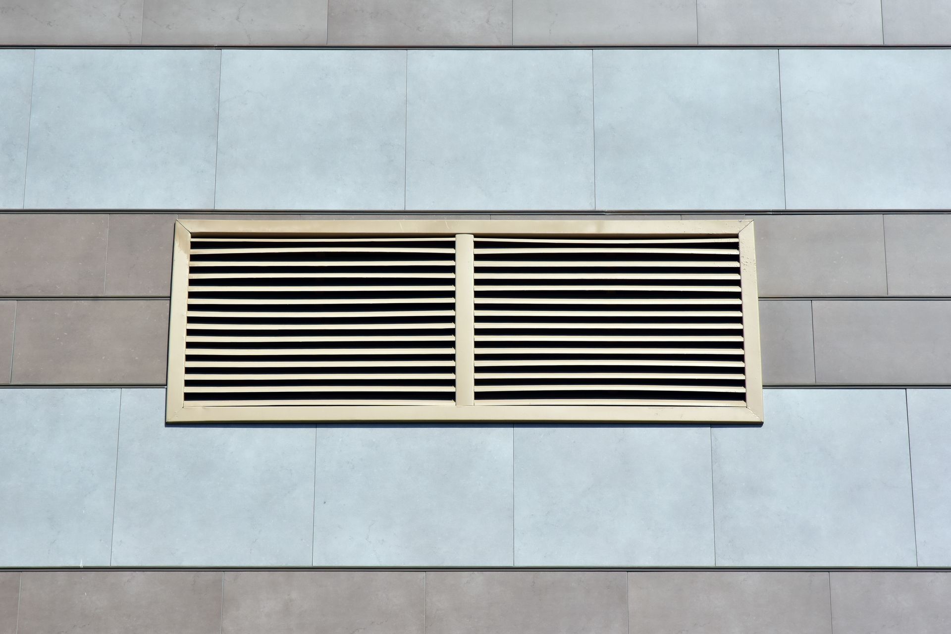 Rectangular air vent with horizontal slats set in a wall with alternating blue and gray panels.