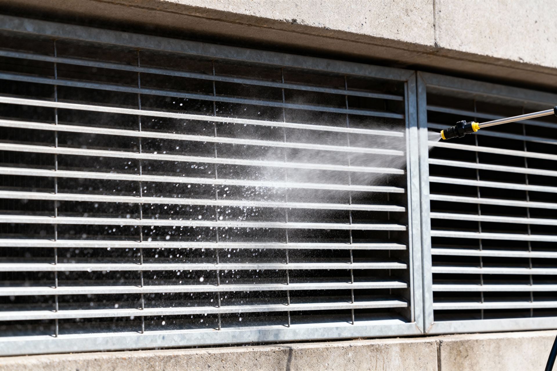 Power washer spraying a metal vent.
