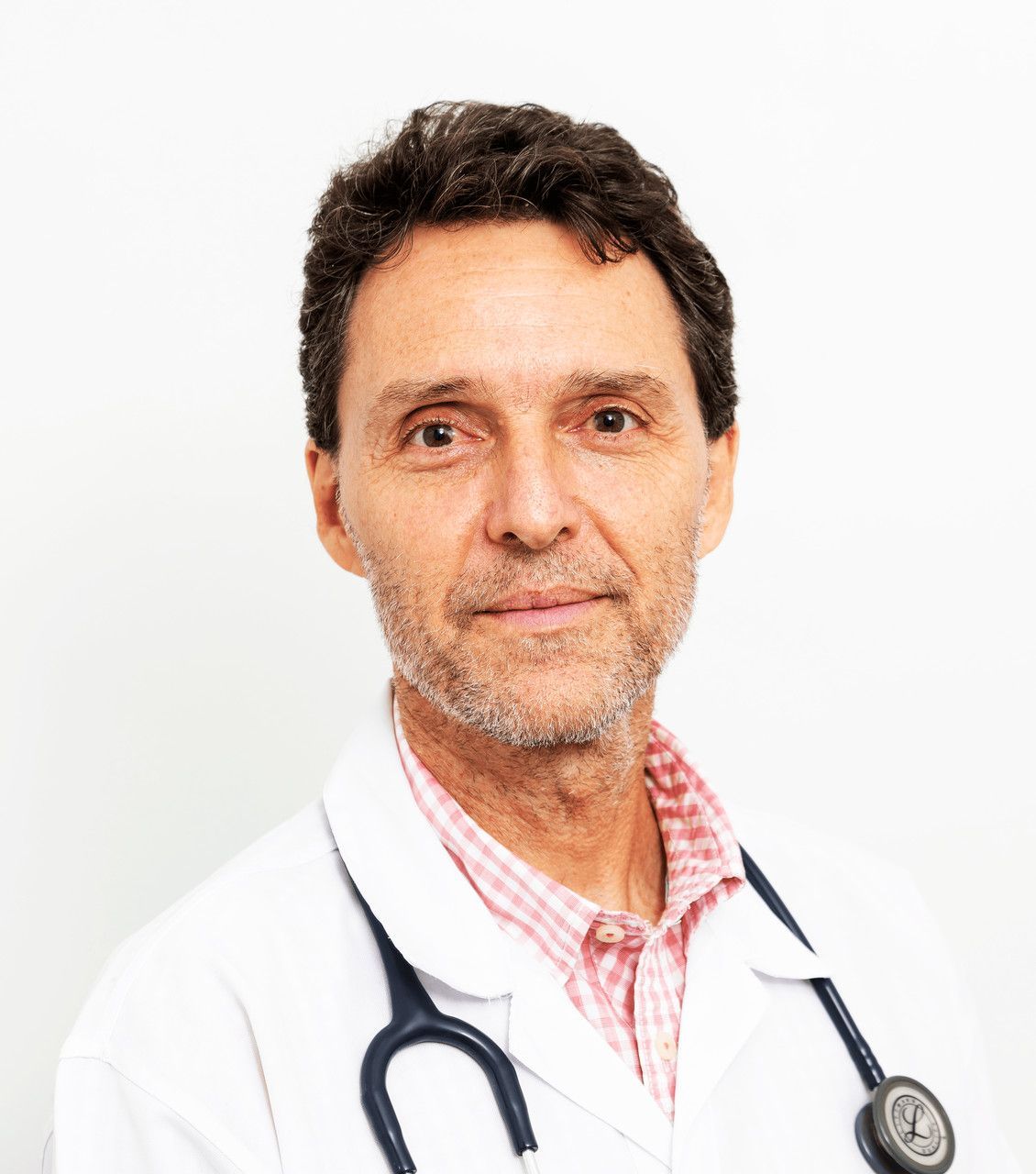 Médico com um estetoscópio no pescoço, vestindo um jaleco branco e uma camisa xadrez rosa.