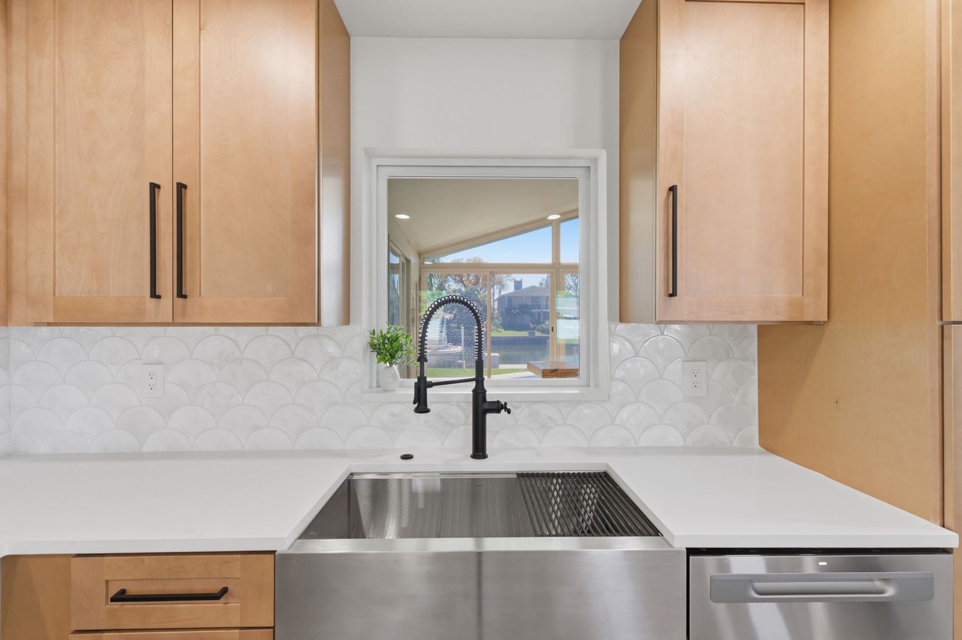 Spacious kitchen with white cabinets, marble backsplash, and wooden island with stools, dark wood floor.