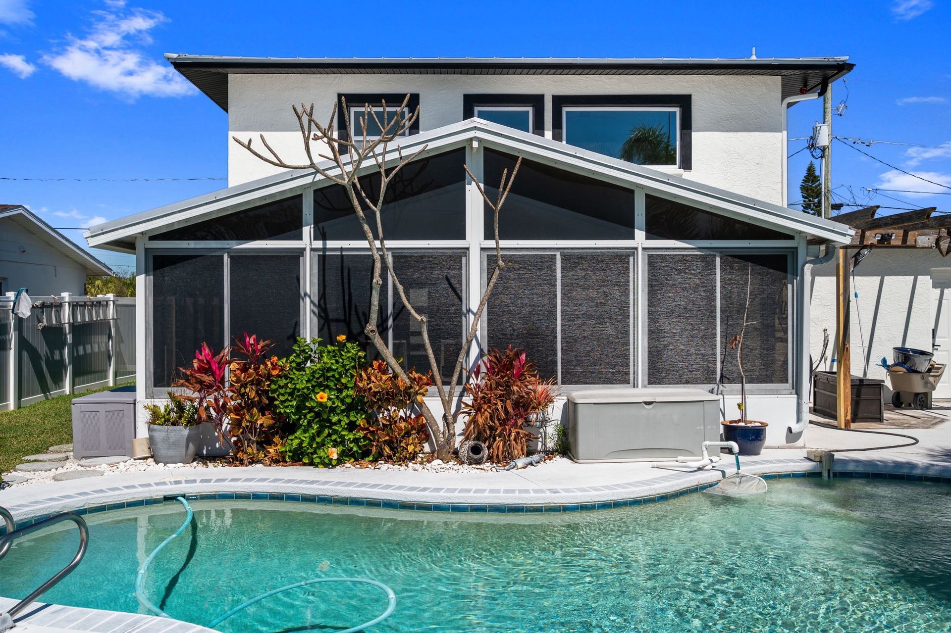 Modern house with large glass windows, wood paneling, and white trim against a blue sky.