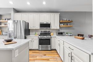 Modern kitchen with a white island, dark cabinets, and globe pendant lights.