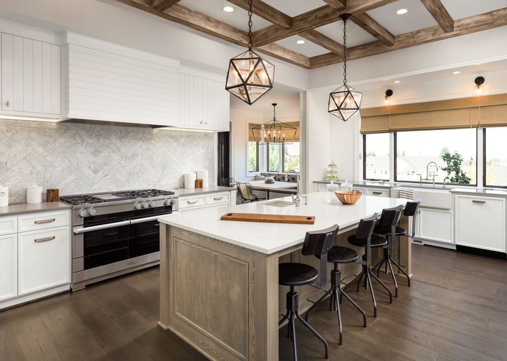 Spacious kitchen with white cabinets, marble backsplash, and wooden island with stools, dark wood floor.