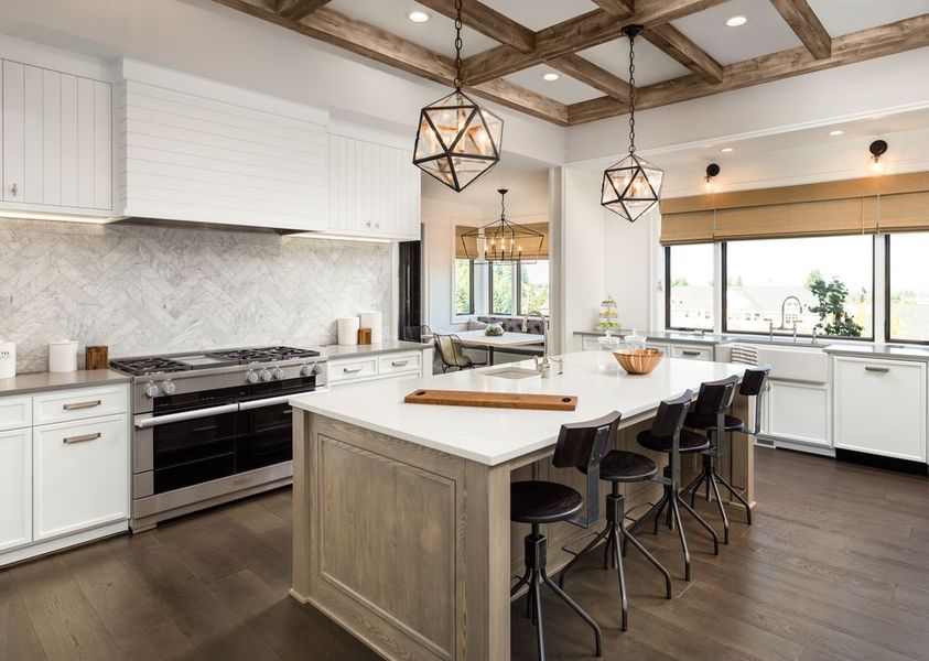 Spacious kitchen with white cabinets, marble backsplash, and wooden island with stools, dark wood floor.