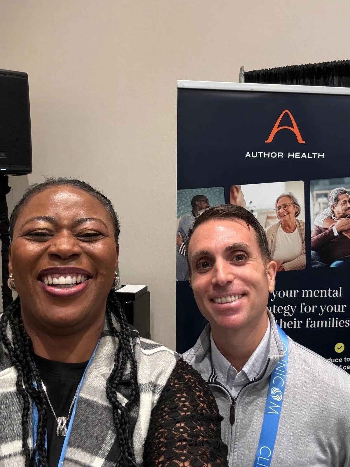 Two people smiling at a conference booth with an Arthur Health banner in the background