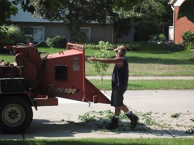 A man is pushing a tornado tree chipper down the street