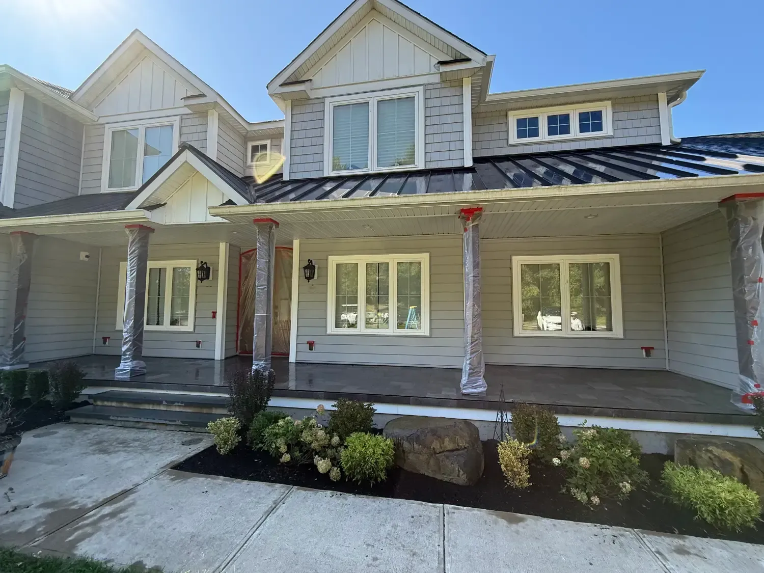 Two-story house exterior with gray siding, white trim, and a covered front porch