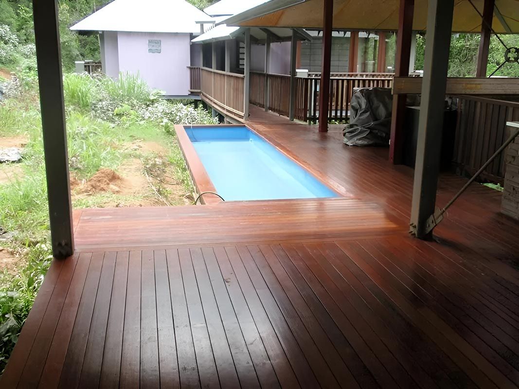 A Wooden Deck With A Swimming Pool In The Background — Justmill Carpentry & Building in Smithfield, QLD
