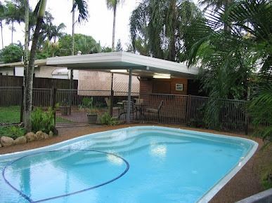 A Large Swimming Pool In The Backyard Of A House Surrounded By Palm Trees — Justmill Carpentry & Building in Smithfield, QLD