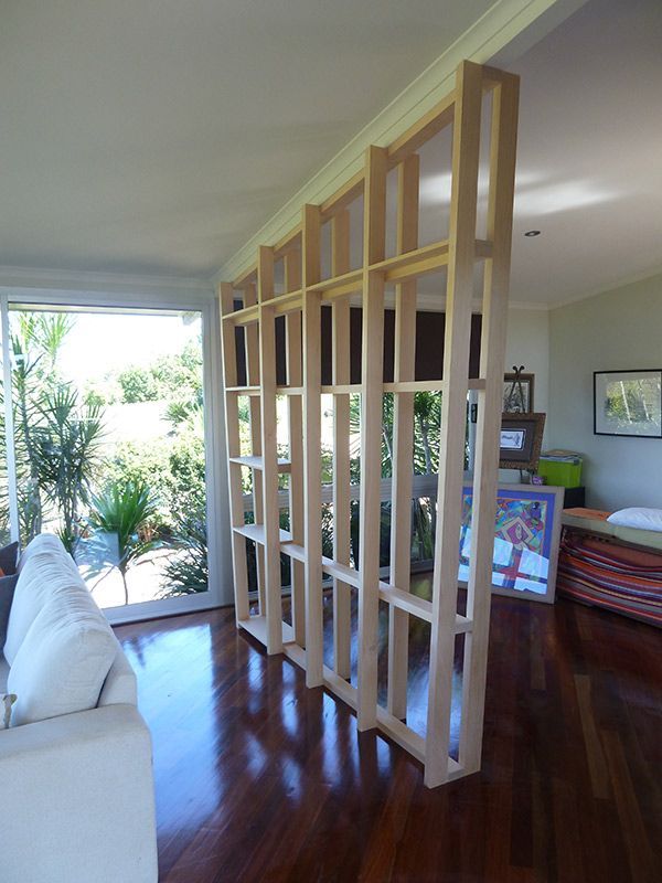 A Living Room With A White Couch And A Wooden Room Divider — Justmill Carpentry & Building in Smithfield, QLD