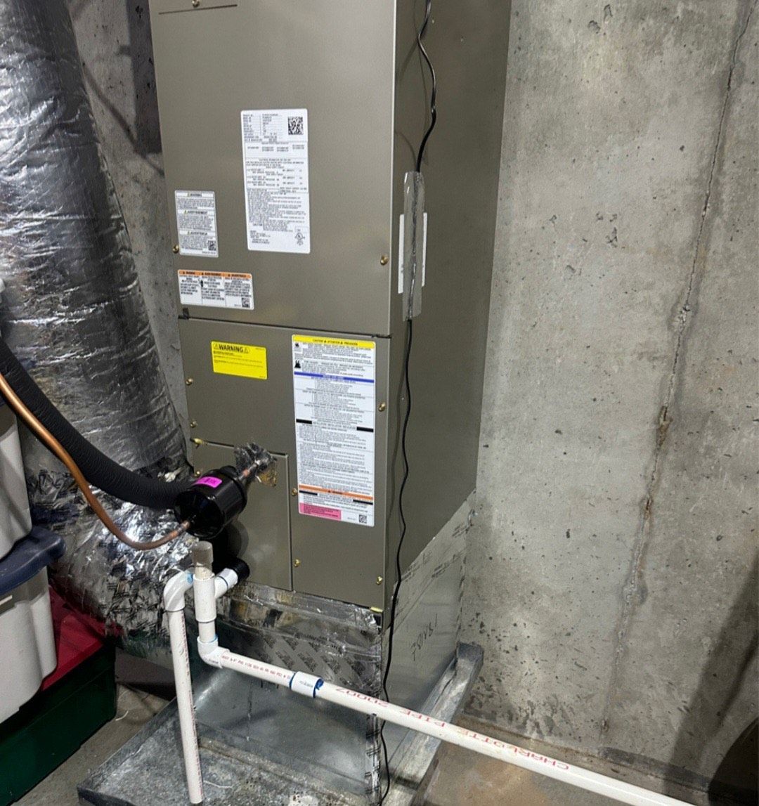 An air conditioner is sitting in a basement next to a pipe.