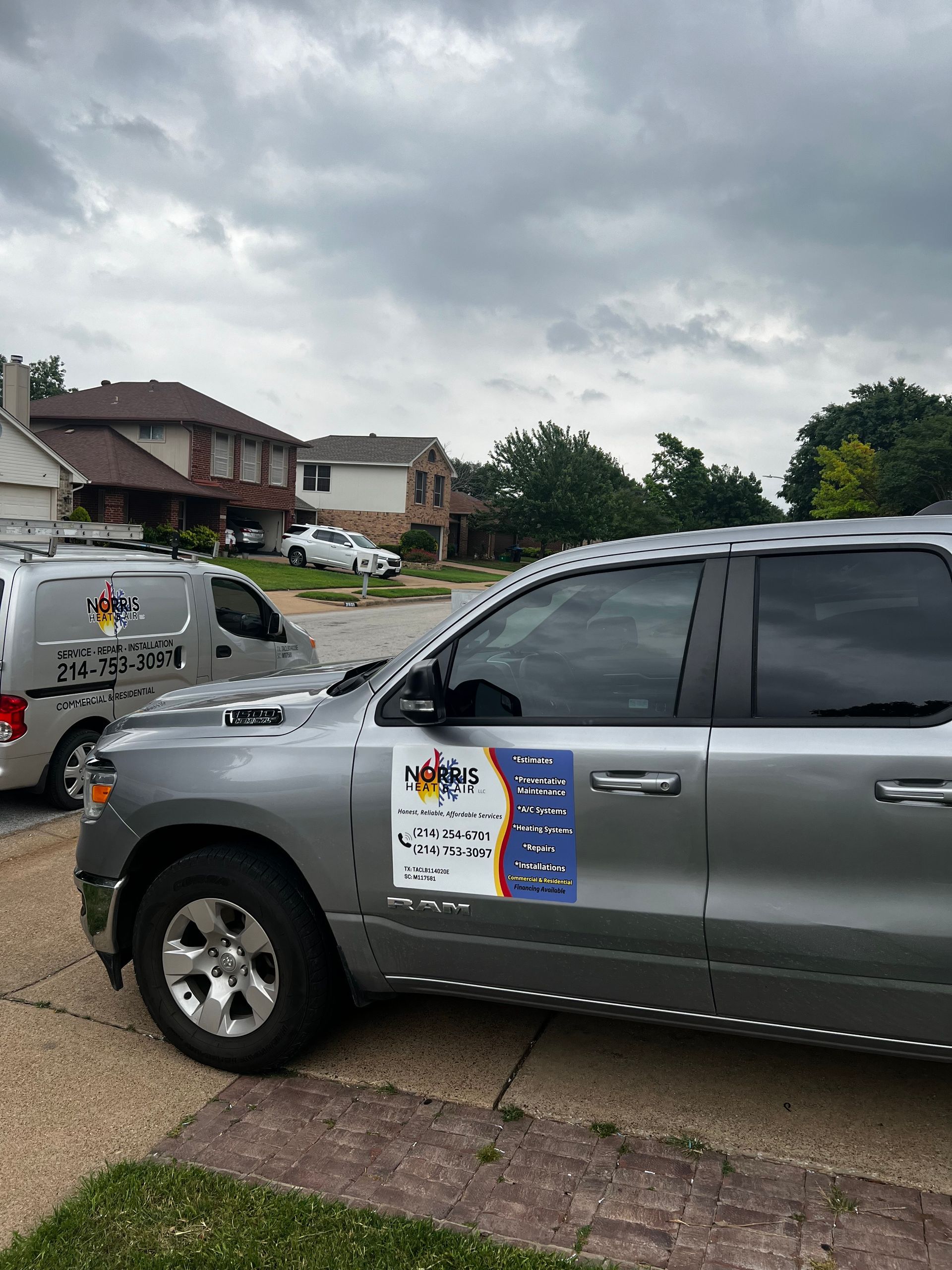 A silver truck is parked in a driveway in front of a house.