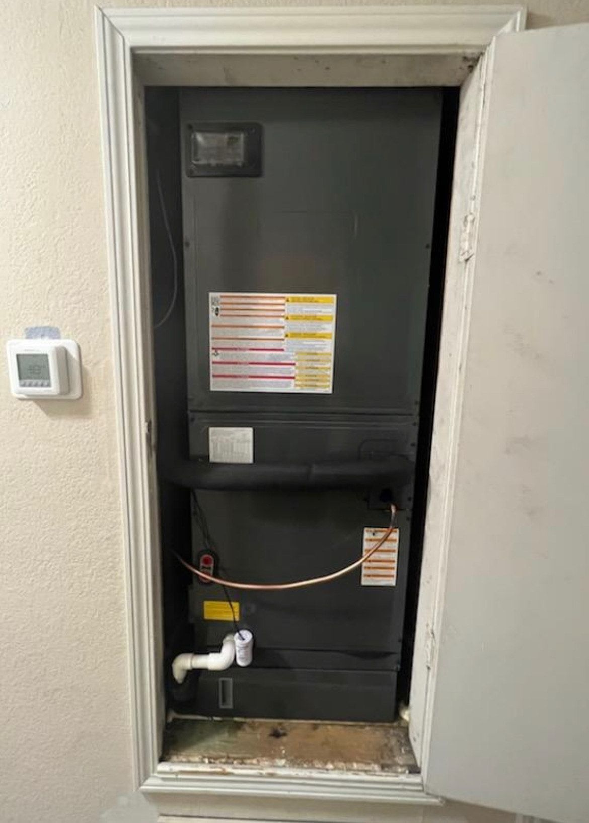 An air conditioner is sitting inside of a doorway in a room.