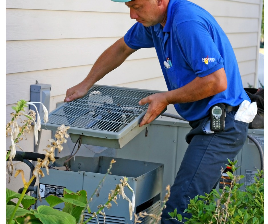 A man in a blue shirt is working on an air conditioner