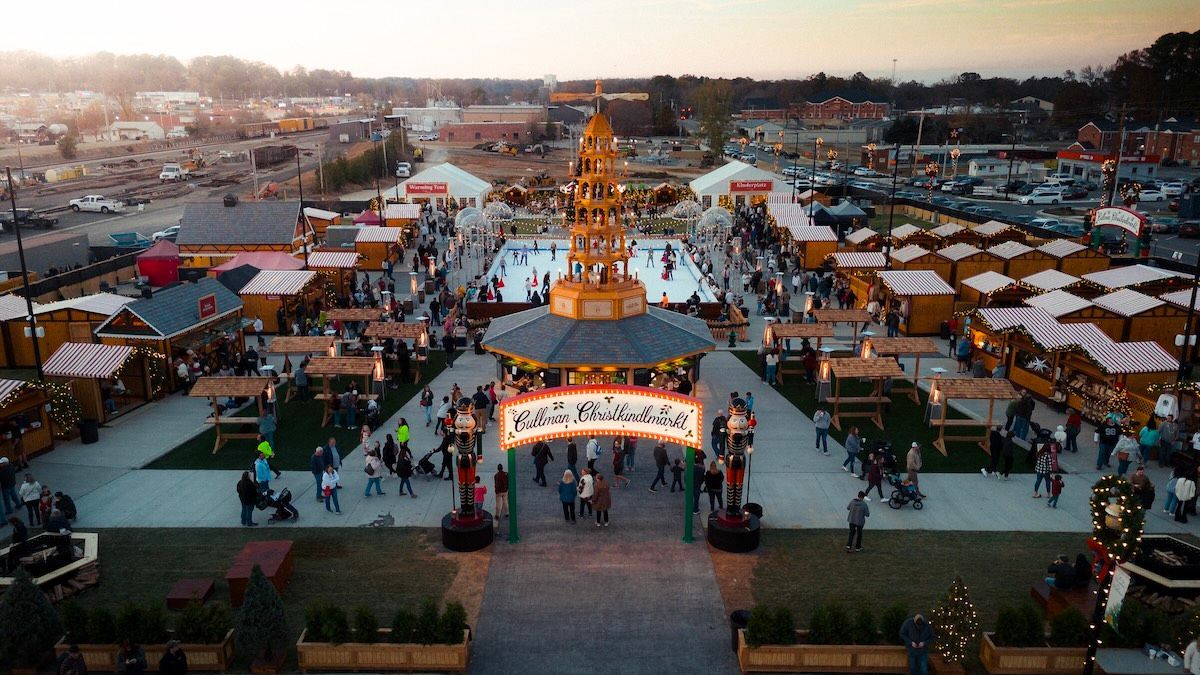 An aerial view of a christmas market with a large christmas tree in the middle.