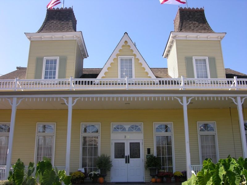 A yellow house with two flags on top of it