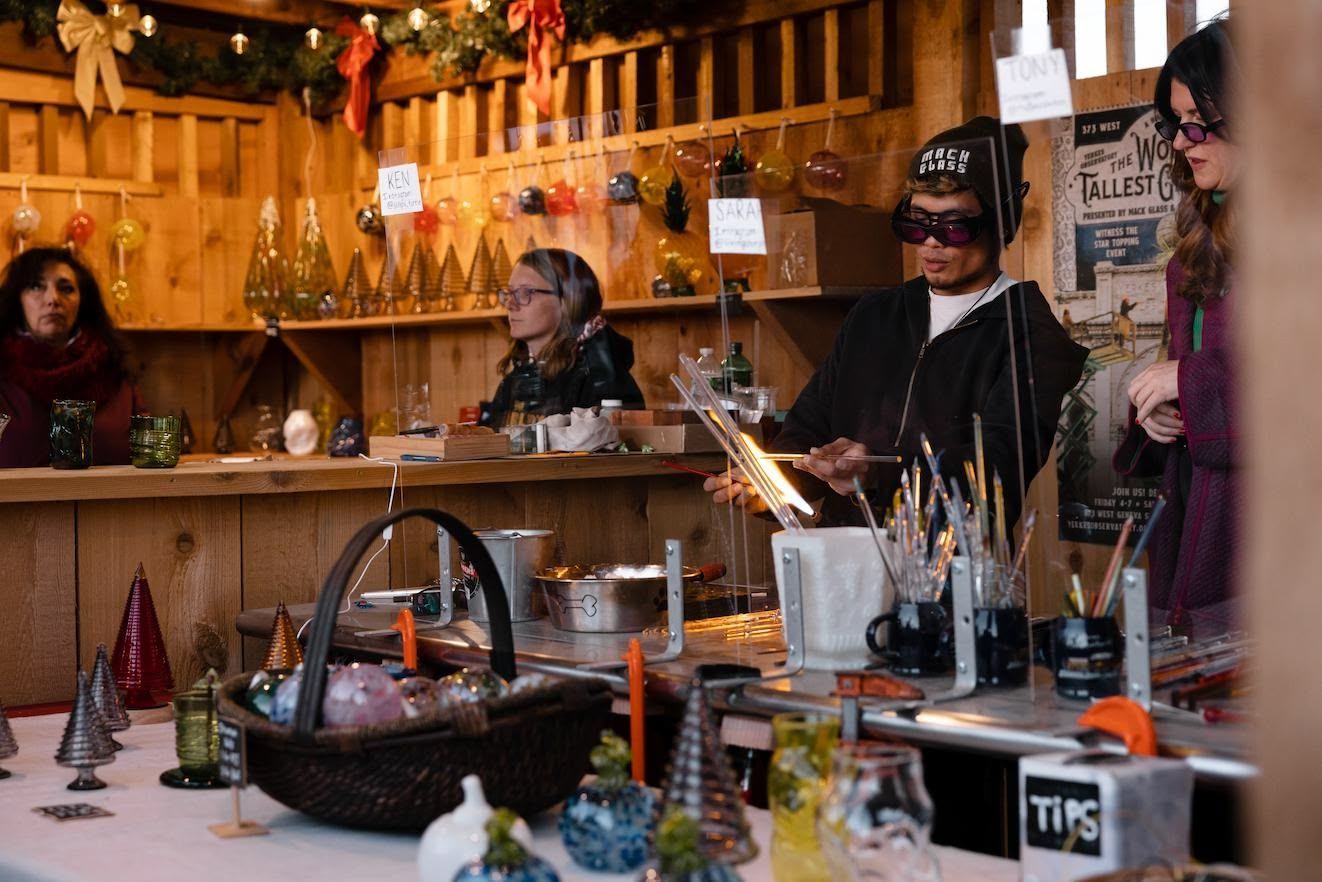 Two men are working on a christmas tree made out of bottles.