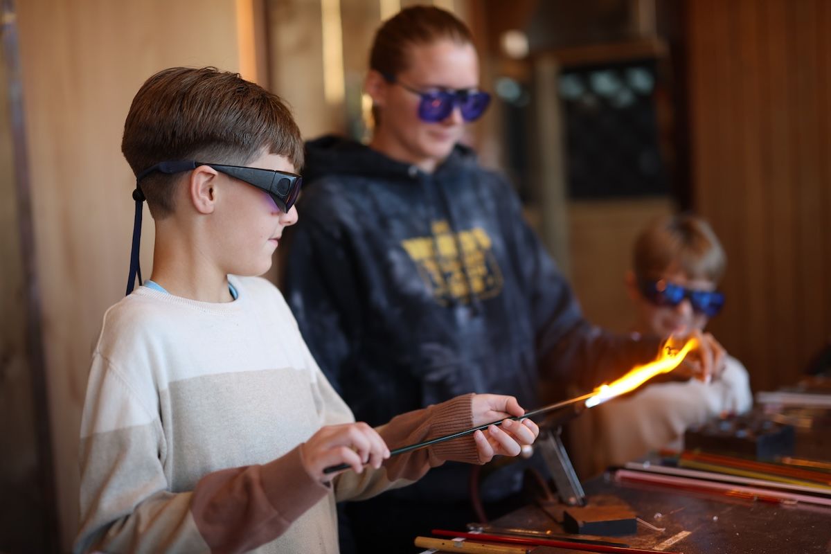 A man wearing a br shirt is blowing glass