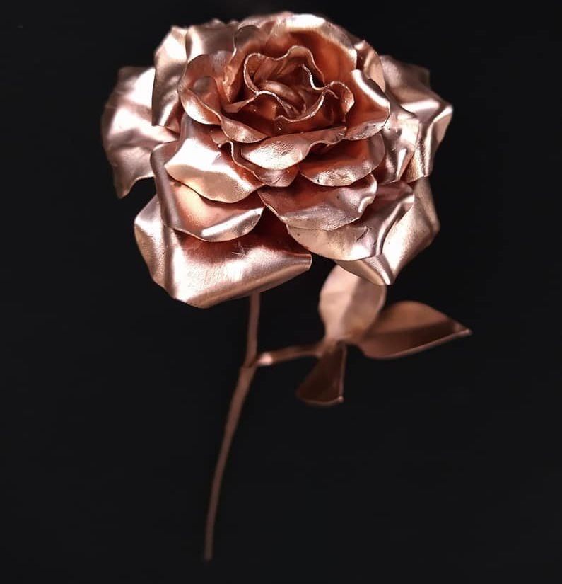 A close up of a copper rose on a black background