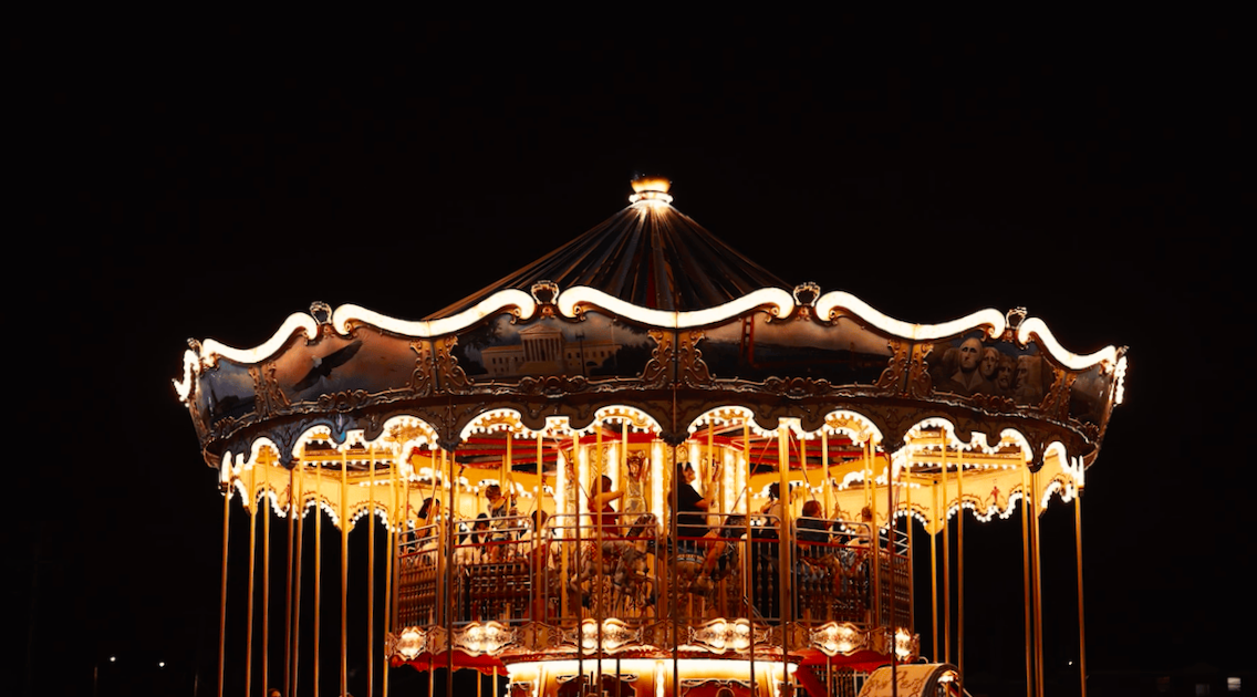 A group of people are riding a merry go round at night.