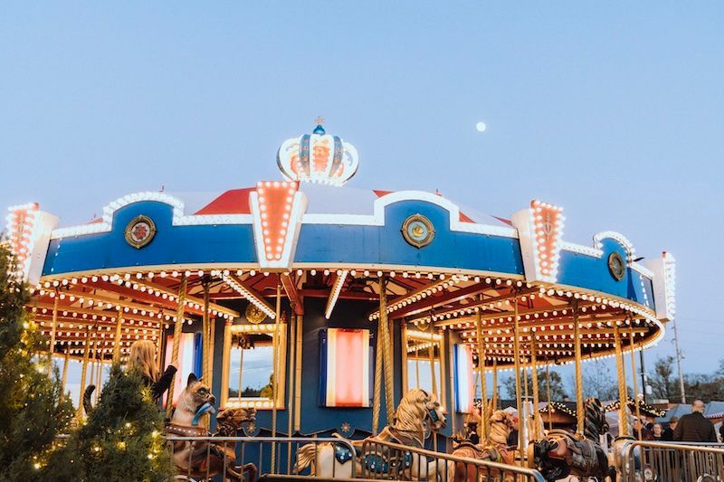 A merry go round at an amusement park with a crown on top of it.