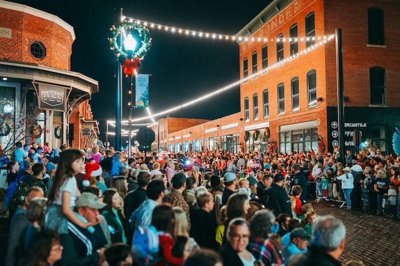 A crowd of people are gathered on a city street at night.