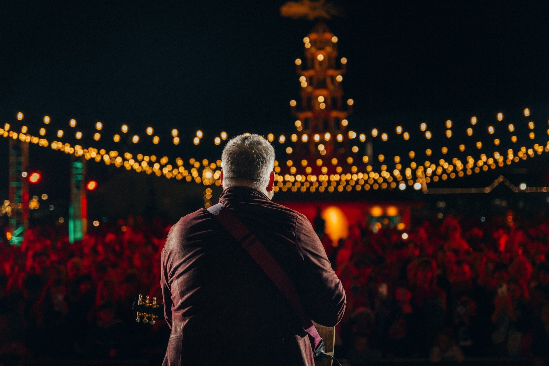 A man is playing a guitar in front of a crowd at a concert.