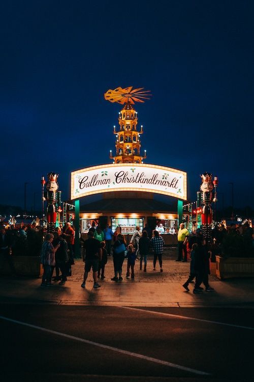 A group of people are standing in front of a carnival at night.