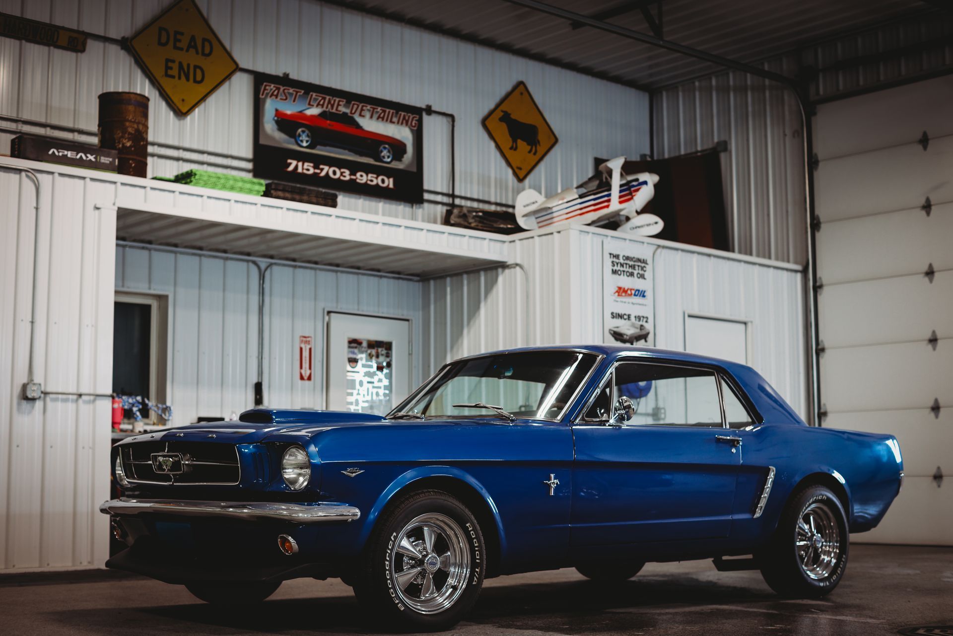 Blue classic car in a garage with racing signs and a checkered floor
