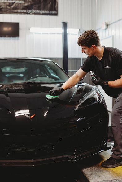 A person is polishing the hood of a blue car.