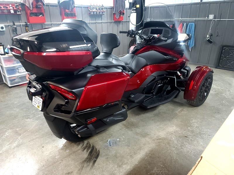 A red motorcycle with three wheels is parked in a garage.