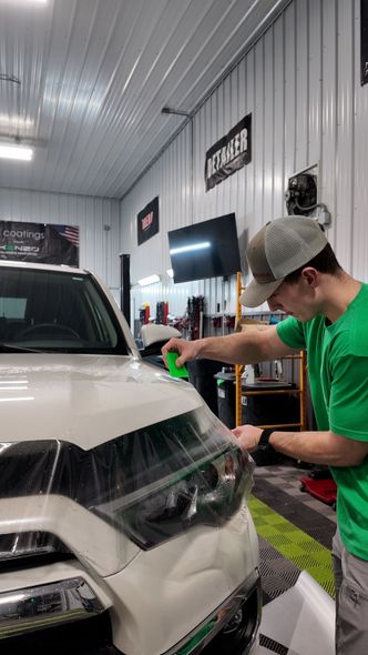 A person is cleaning a car with a blue sponge.