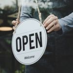 A person is holding a sign that says open welcome