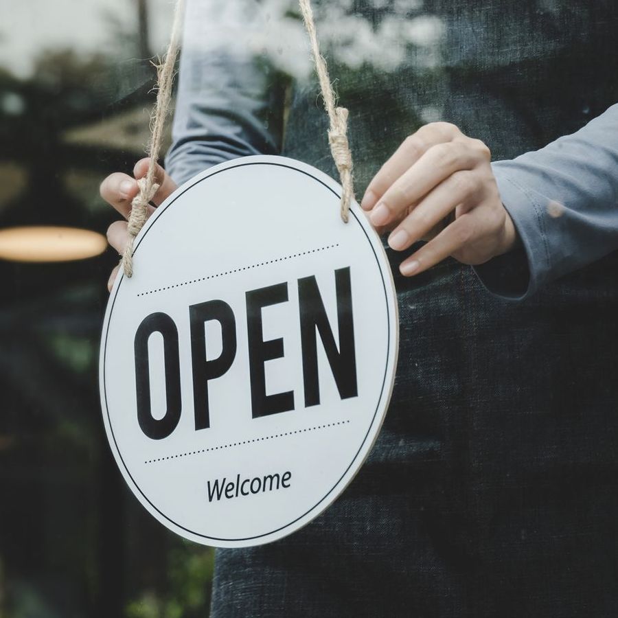 A person is holding a sign that says open welcome