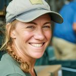 A woman wearing a baseball cap is smiling for the camera