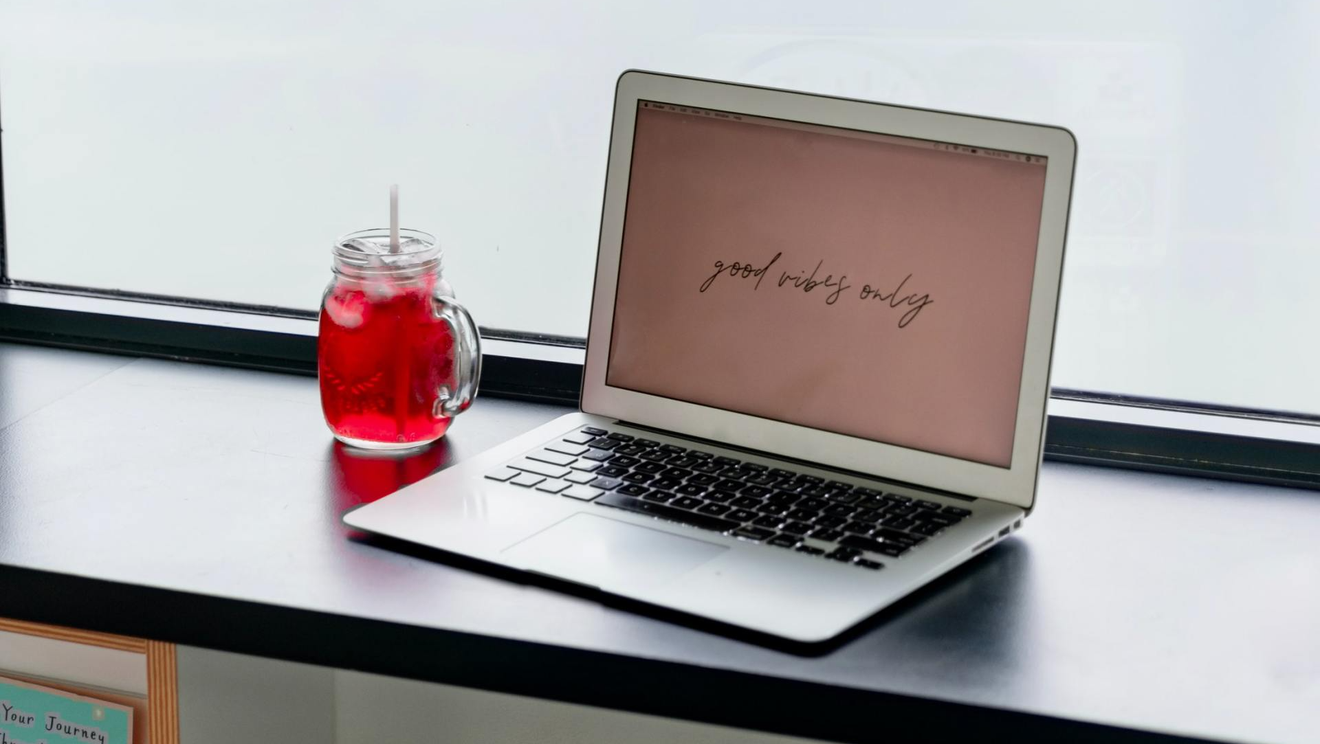 pantalla de computadora con frase inspiradora con paisaje de fondo y un vaso de jugo