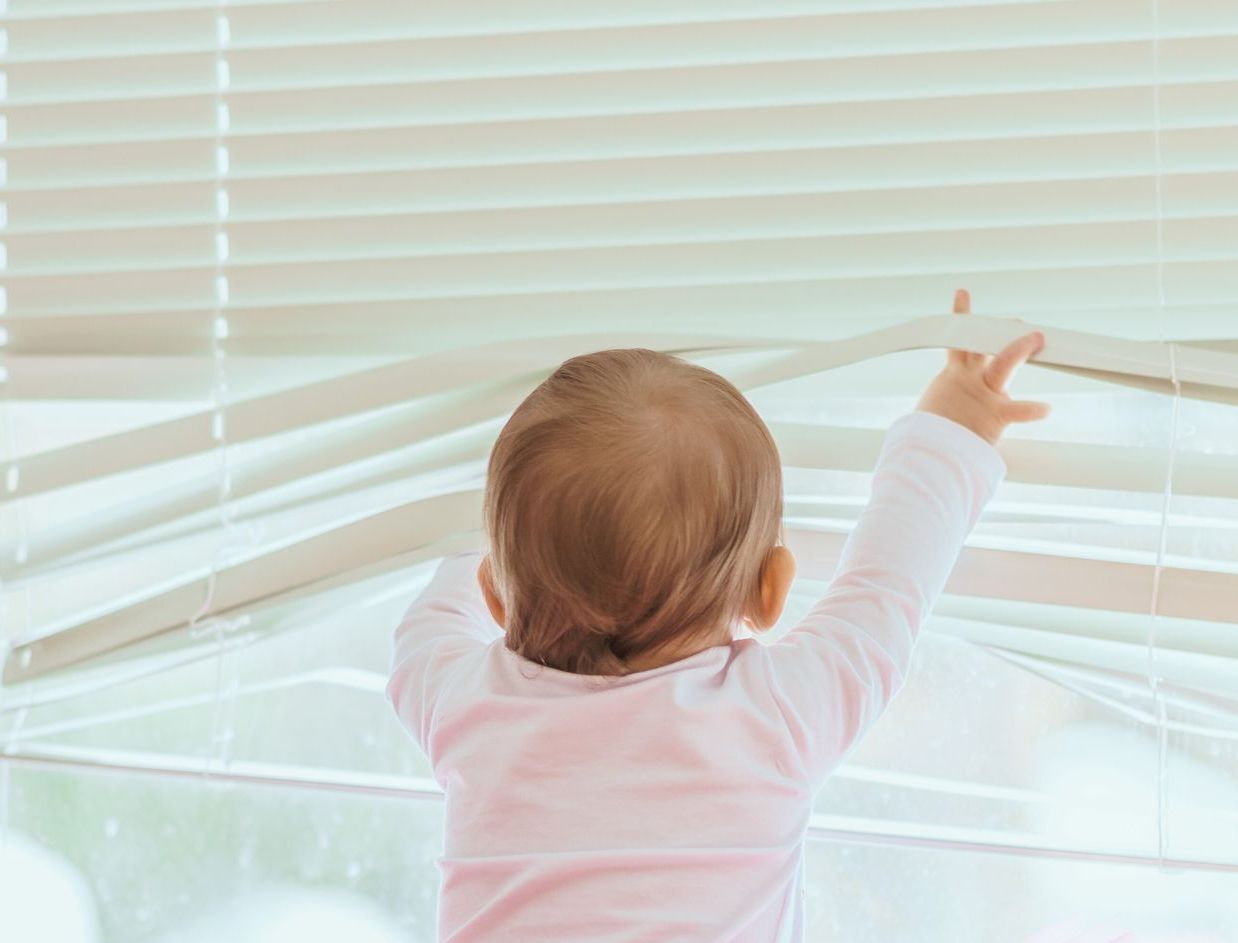 baby with hands in blinds
