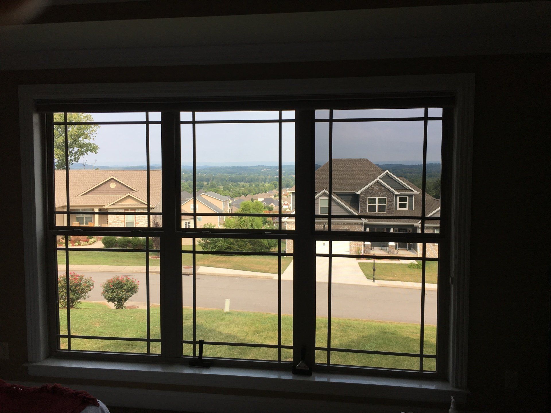 A large window with a view of a house and a street.